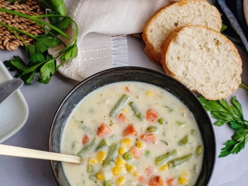 A bowl of low carb vegetable soup next to bread