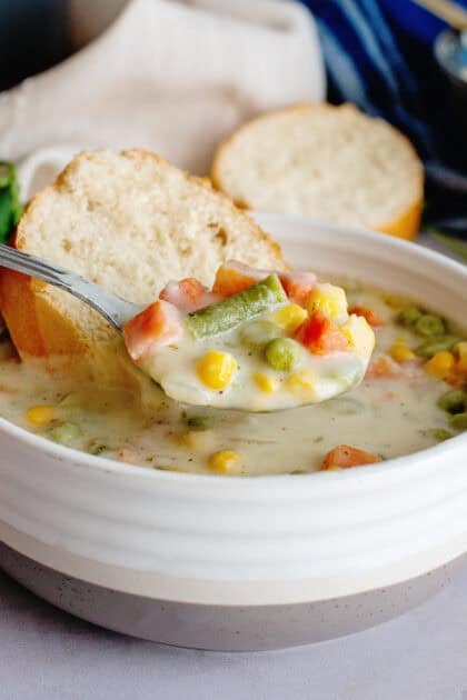 Side view of creamy low carb vegetable soup with a side of bread