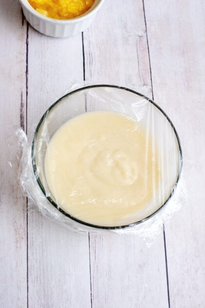 Covering the Frog Eye Salad custard with cling wrap for cooling