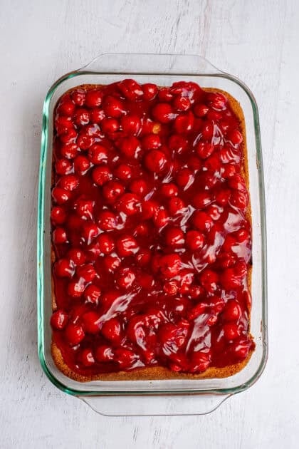 Smoothing out the layer of cherry pie filling on the lemon cherry cheesecake