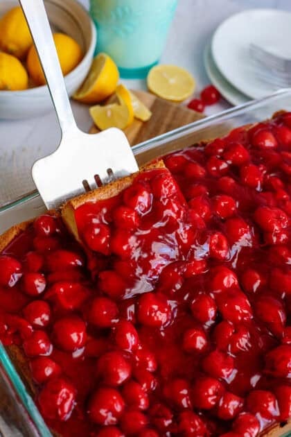 Taking a piece of lemon cherry cheesecake with a spatula