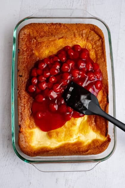 Adding cherry pie filling to the baked lemon cherry cheesecake base