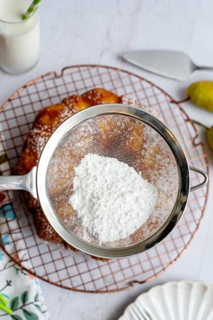 Sprinkling powdered sugar on the baked pear bundt cake