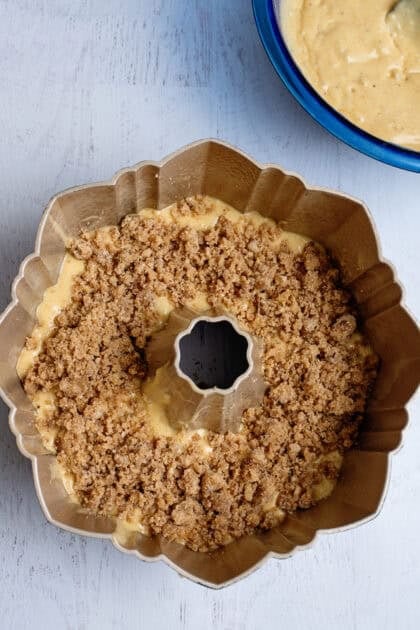 Cinnamon streusel sprinkled on pear bundt cake batter 