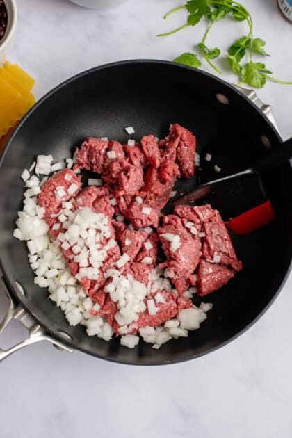 Raw ground beef and raw chopped onion in a skillet