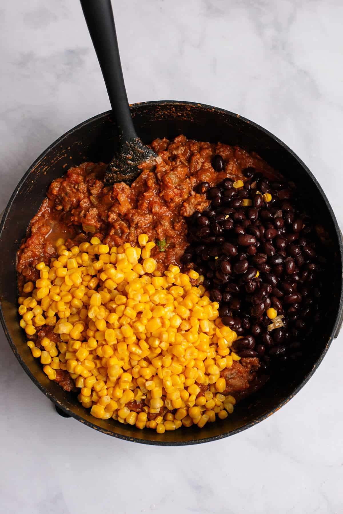 Drained corn and black beans being added to a pan with other Tex Mex Lasagna ingredients
