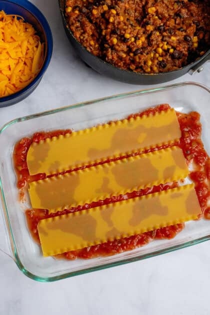 Lasagna noodles being layered in a baking dish