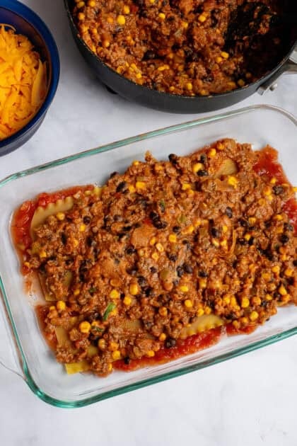 Tex Mex Lasagna filling being layered in a baking dish