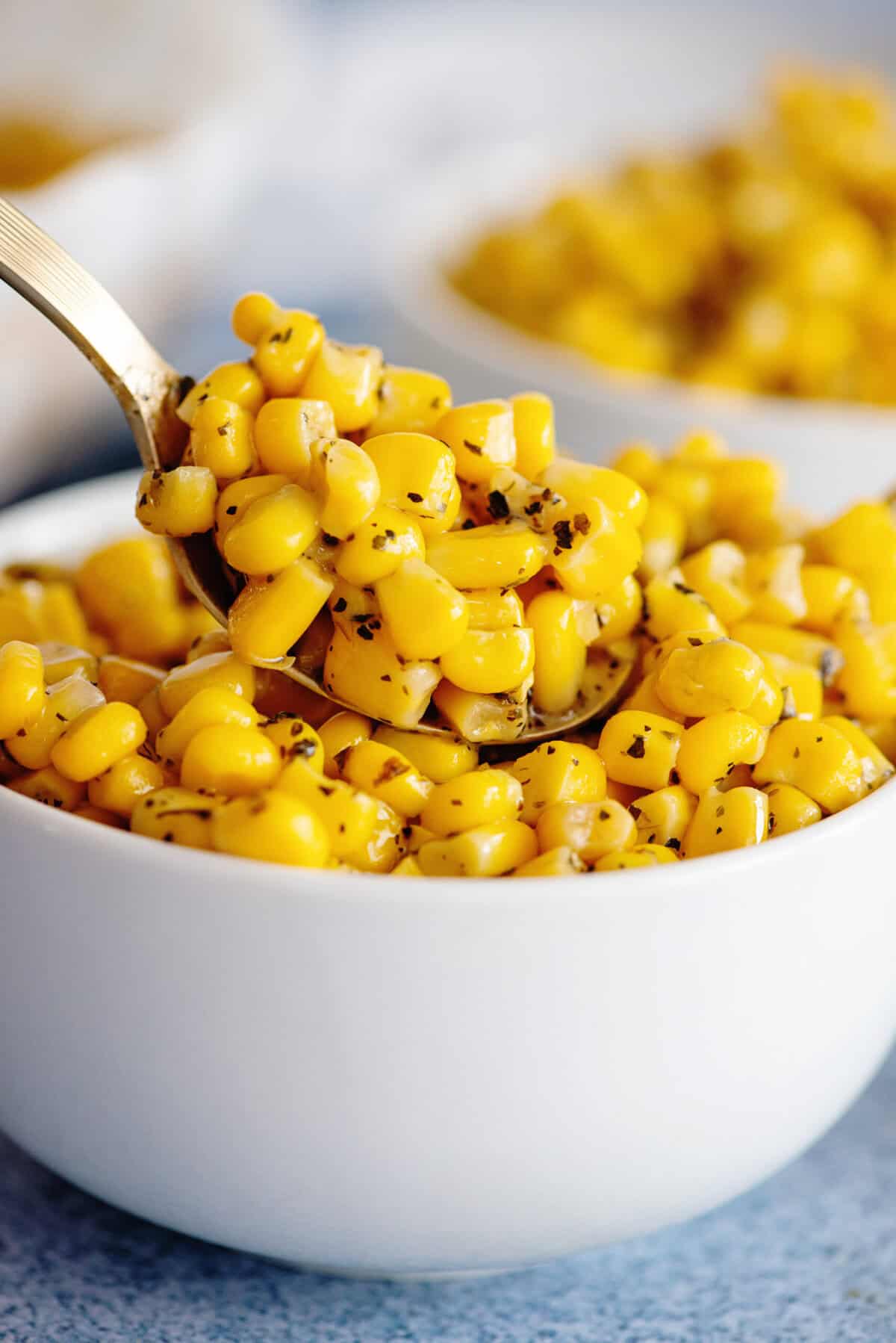 Side view of a bowl of Basil Corn with a spoon