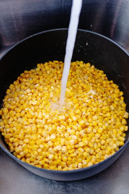 Pouring water over frozen corn in a pot