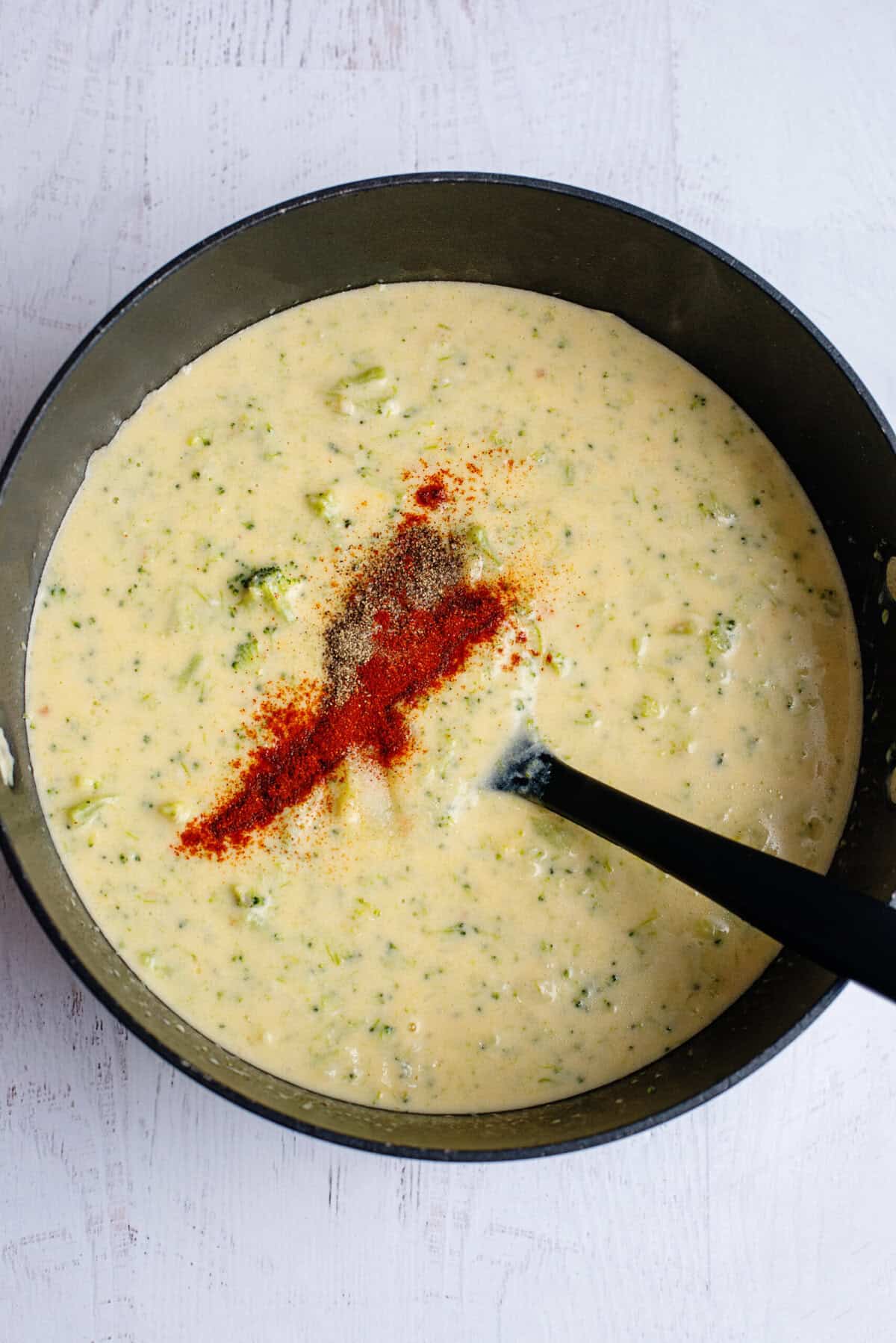 Adding seasoning to Broccoli Cheese and Bacon Soup
