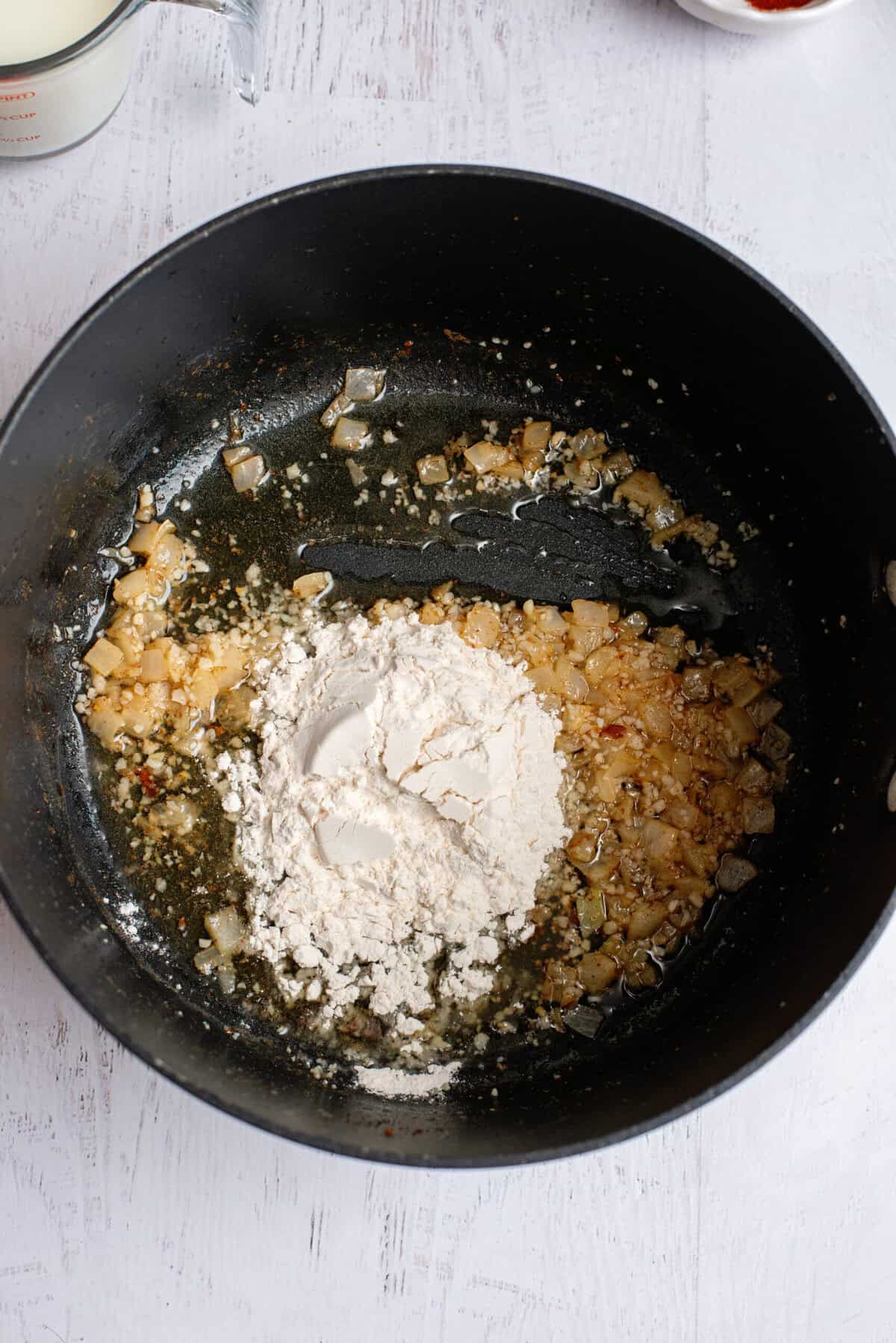 Adding flour to a pan of cooked onion and garlic