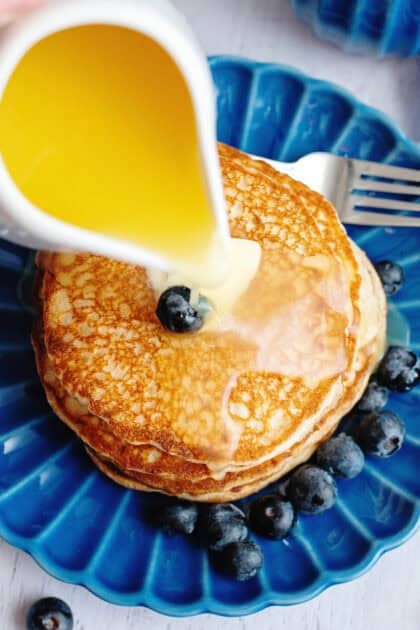 Top view of homemade buttermilk syrup being poured on a stack of pancakes