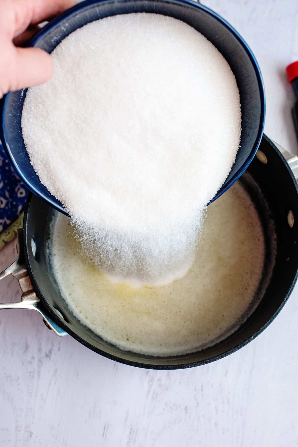 Adding sugar to a pot of melted butter