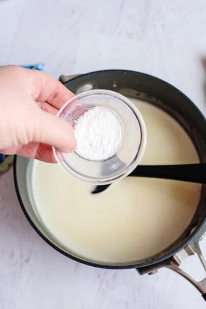 Adding baking soda to the pot of buttermilk, butter, and sugar mixture