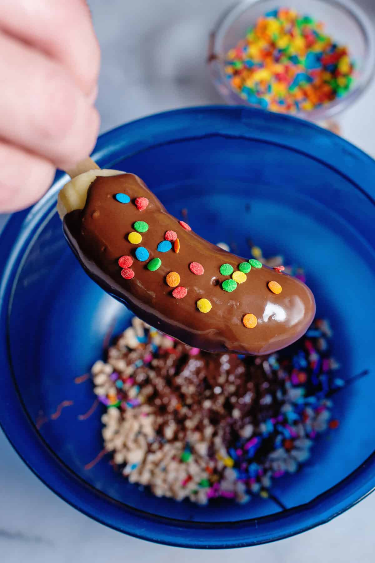 Adding sprinkles to a freshly dipped banana
