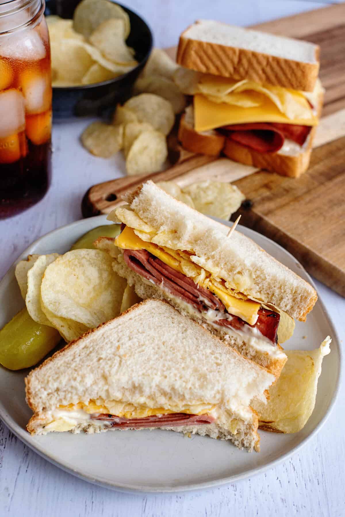 A plate with sliced fried bologna sandwich and chips