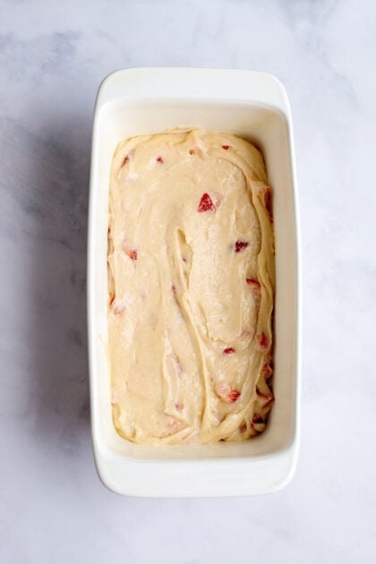 Pouring strawberry bread mixture into a baking pan