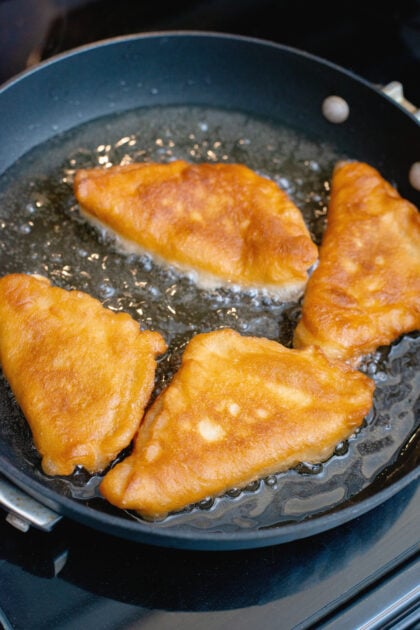 brown and crispy raspberry and chocolate beignets in a frying pan with oil