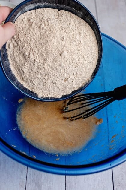 Adding flour to the bowl of peanut butter and water
