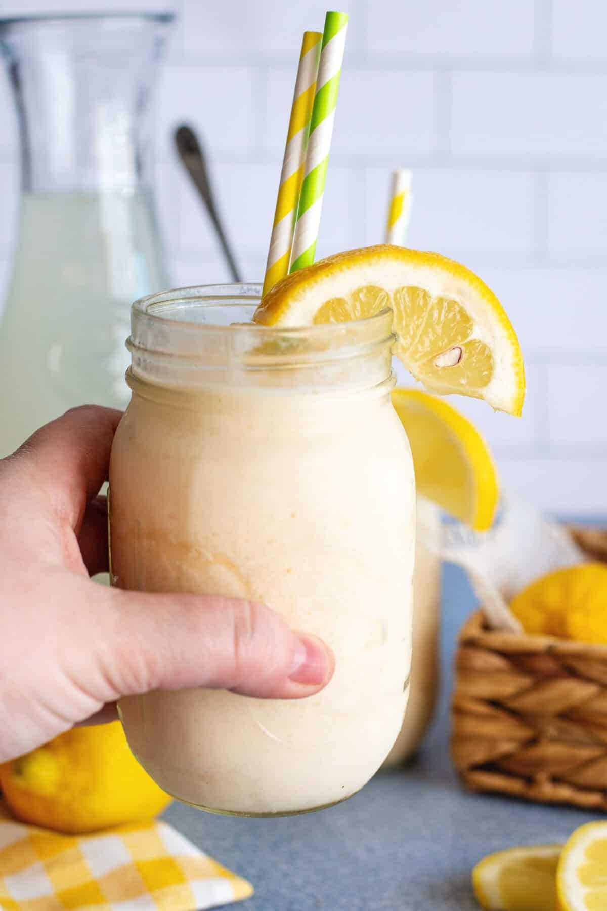a hand holding a delicious looking chilled glass of frozen lemonade.