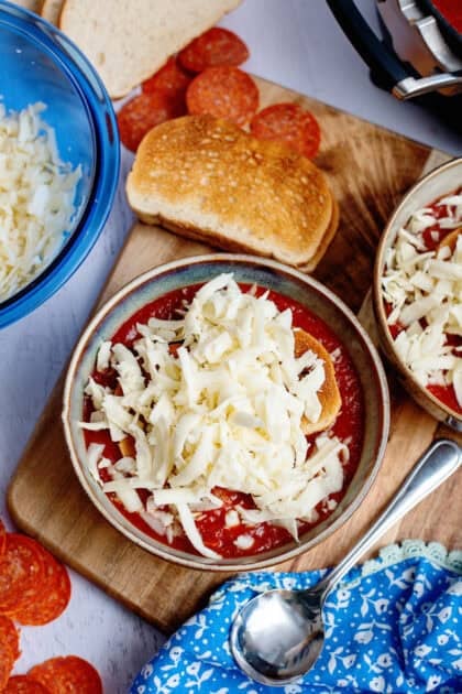 Adding shredded mozzarella to the pizza soup