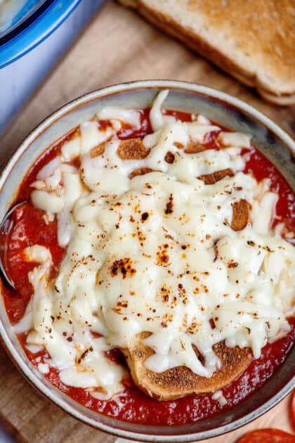 Melted mozzarella over a slice of toast and a bowl of pizza soup