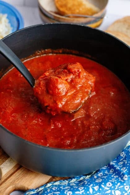 Taking meatballs out of pizza soup with a ladel
