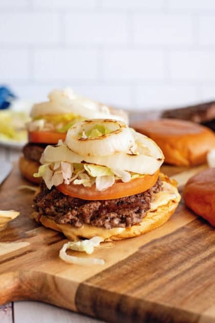 Adding condiments and toppings to an open-face smash burger