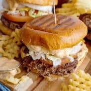 Smash burgers on a serving board with waffle fries