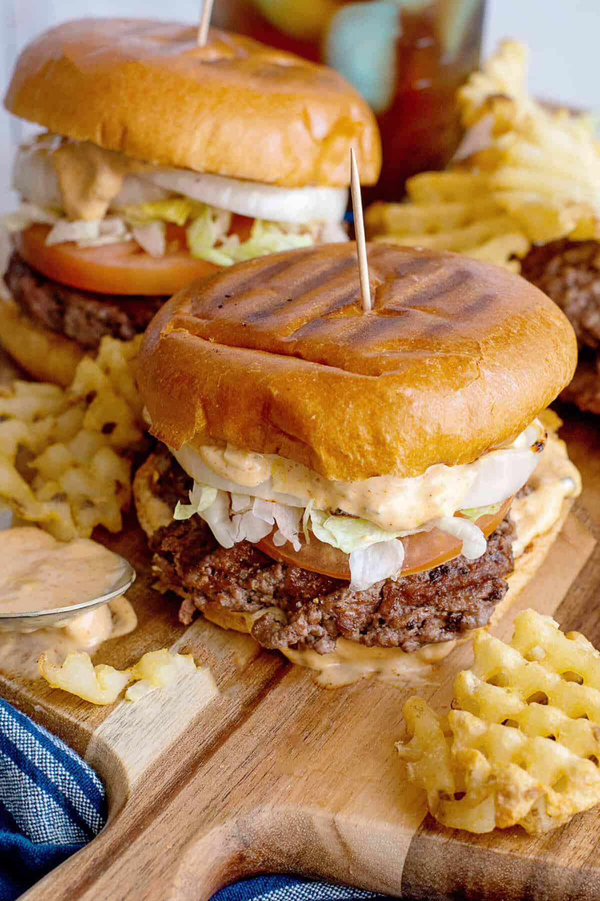 Smash burgers on a serving board with waffle fries