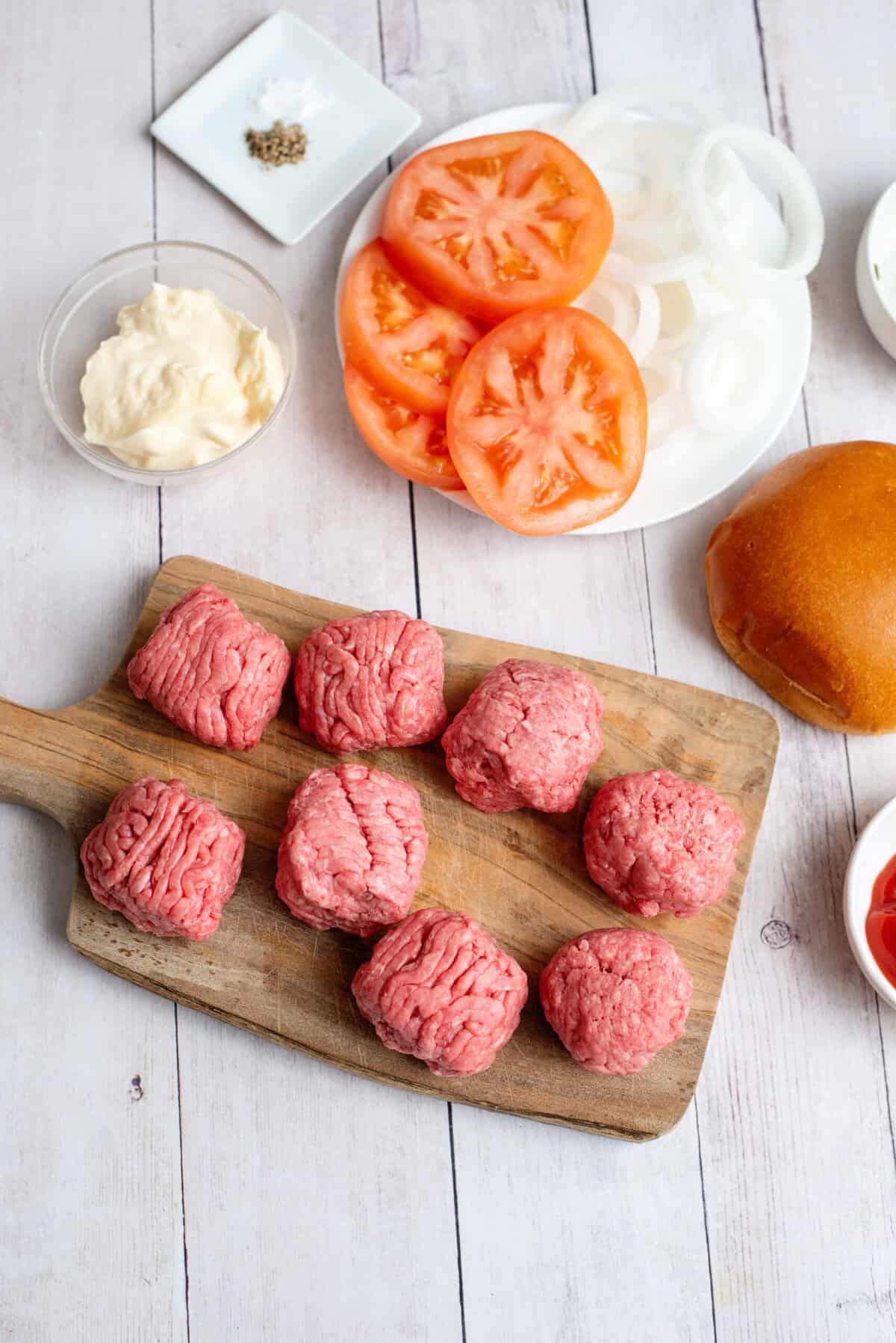 A cutting board with beef balls for the smash burgers