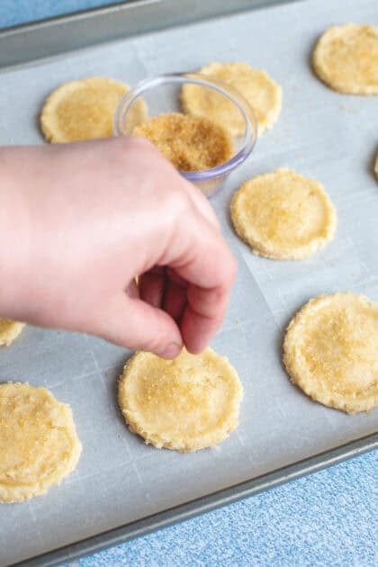 Flattening the old fashioned cookie dough balls on a baking sheet