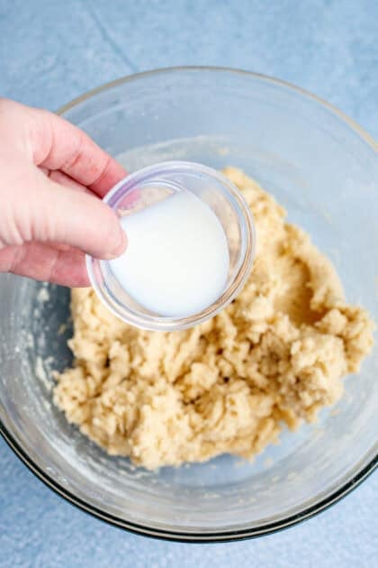 Adding milk to the small bowl of old fashioned butter cookie batter