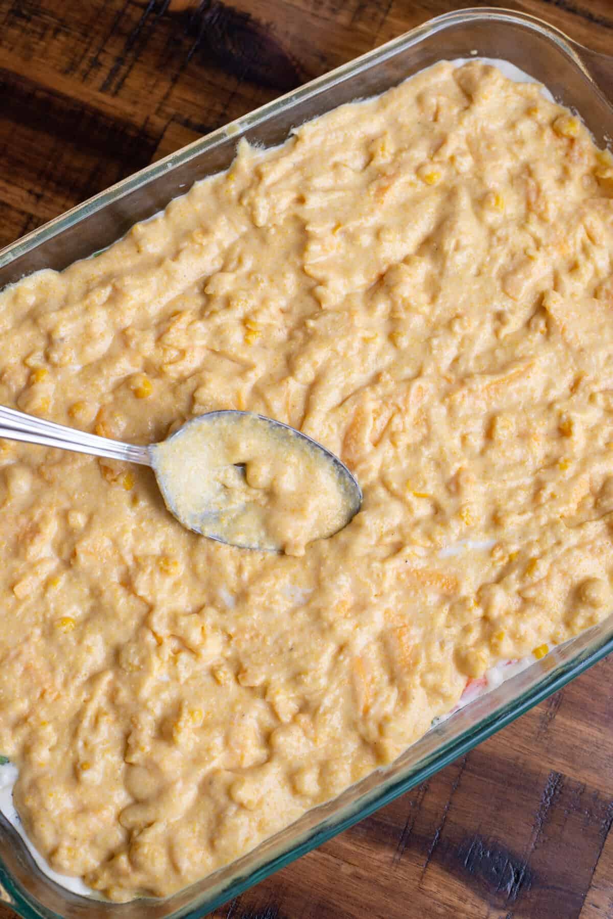 Spreading the cornbread topping over the chicken pot pie filling.