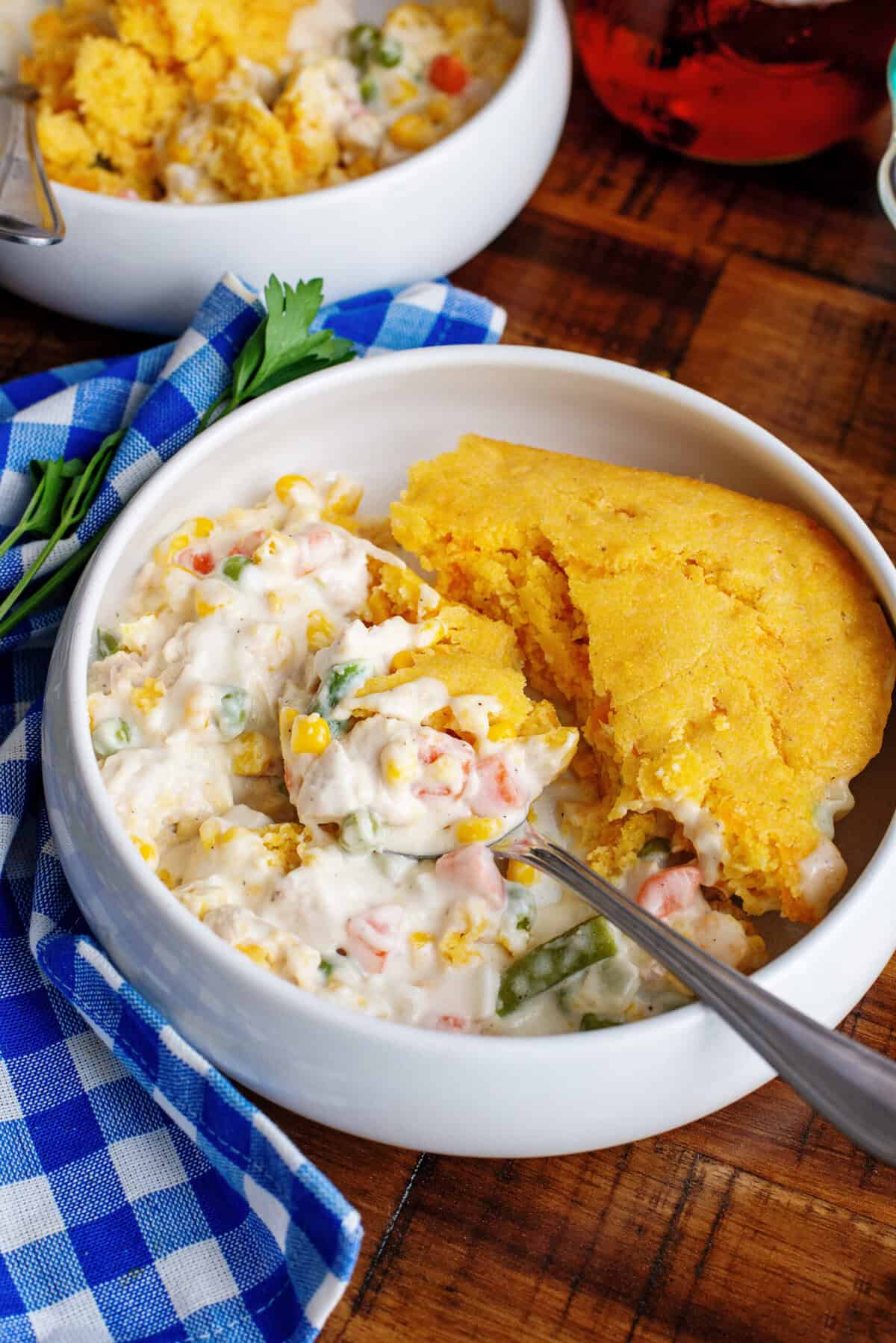 Dipping a spoon into a bowl of cornbread chicken pot pie. 