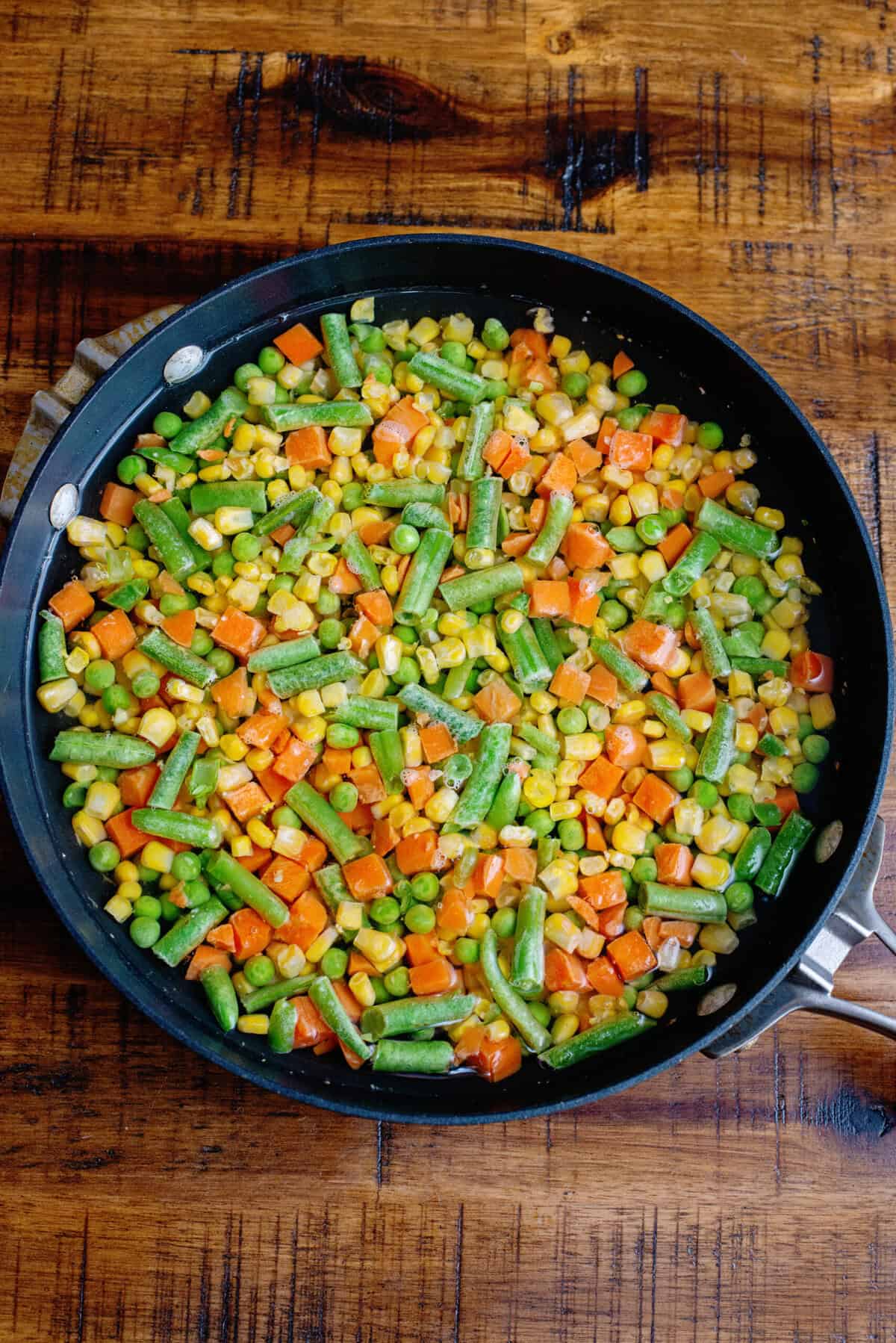 A skillet with frozen mixed vegetables.