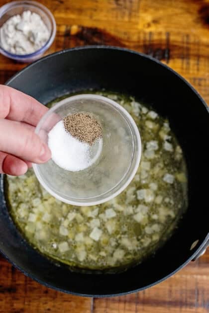 Holding salt and pepper in a small dish over a saucepan of melted butter and diced onion.