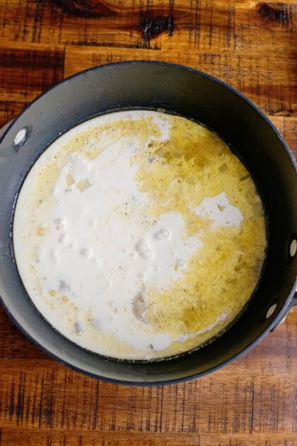 A saucepan of cream, butter, onions, chicken broth, and flour.