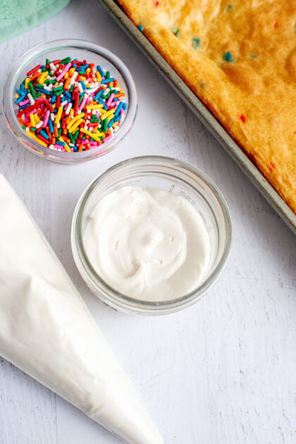 A layer of vanilla frosting on the cake round base layer in a mason jar