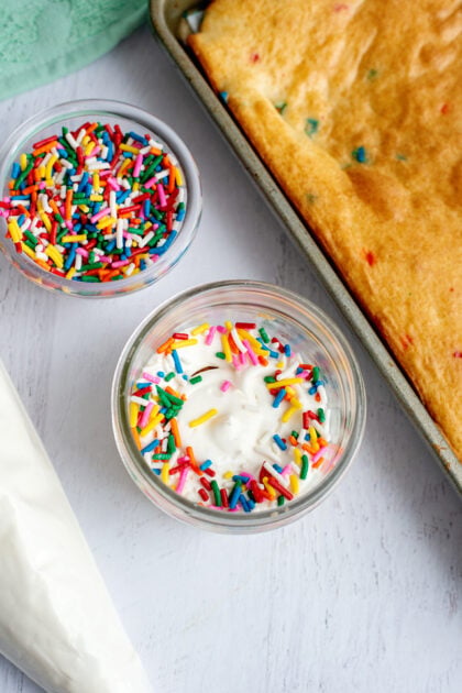 Sprinkles on top of the vanilla frosting layer in a mason jar