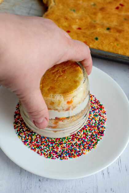 Pressing the Funfetti dot cake jar into a plate of sprinkles