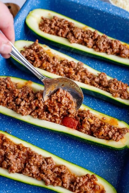 Stuffing the hollowed out zucchini halves with the ground beef mixture