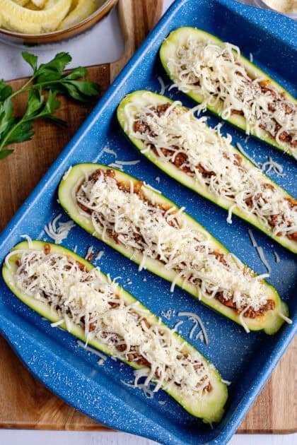 Topping the stuffed zucchini boats with mozzarella cheese