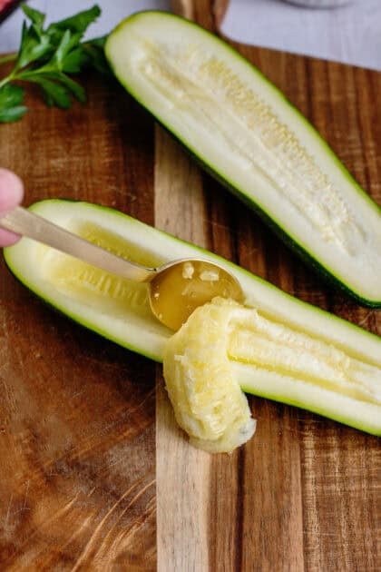 Scooping out the inside of the halved zucchinis with a spoon