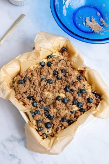 Adding the cinnamon crumb topping to the blueberry coffee cake batter