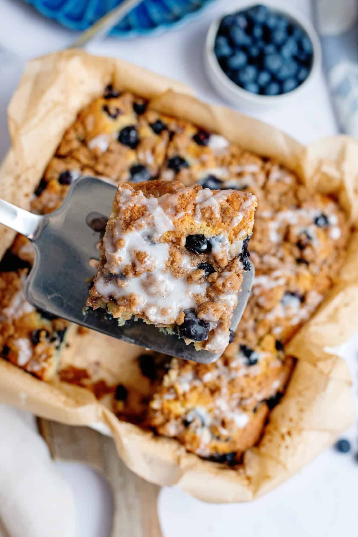 Taking a slice of blueberry coffee cake with vanilla drizzle