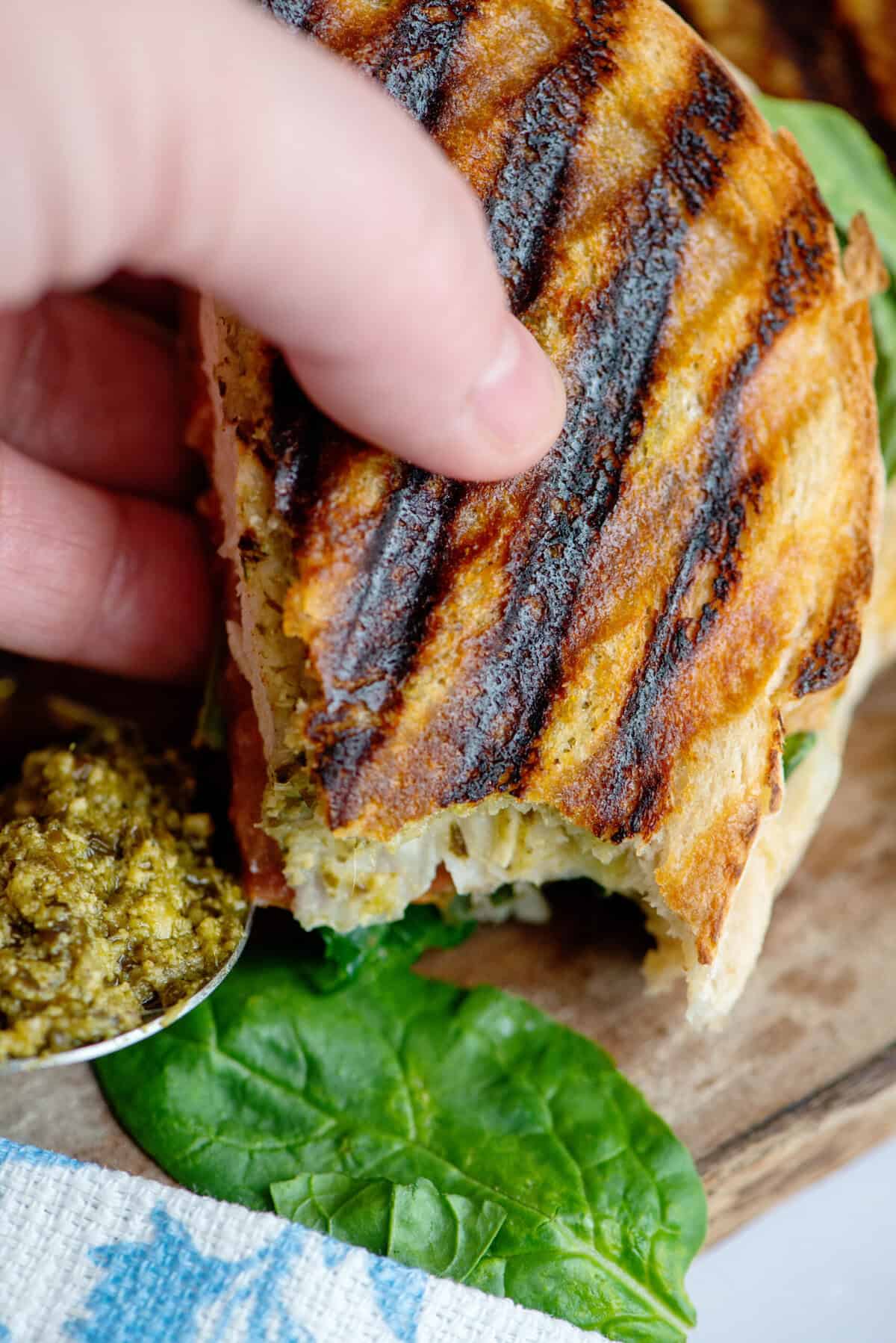 Close up of half a pesto chicken panini with a side of pesto