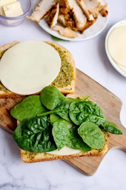 Topping the pesto chicken panini with spinach