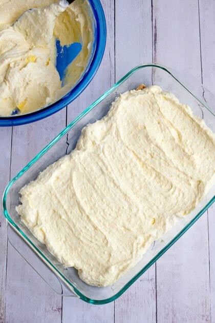 Spreading a layer of vanilla pudding mix over the graham cracker base